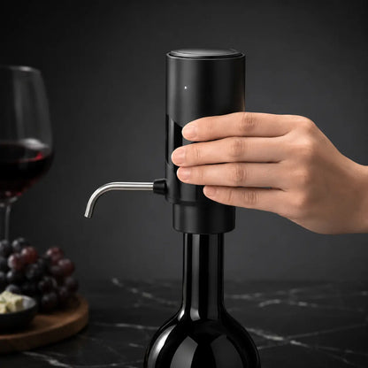 Close-up of hand holding electric wine aerator with stainless steel spout mounted on wine bottle