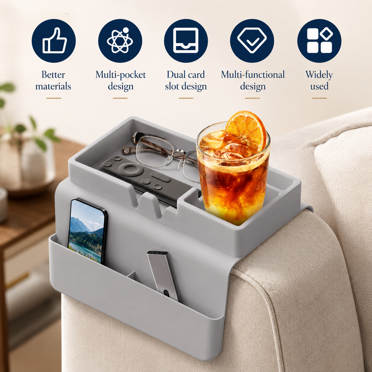Grey silicone couch cup holder on sofa armrest with iced drink, glasses, remote and phone — key features icons showing better materials, multi-pocket design, dual card slot, multi-functional design and wide use.